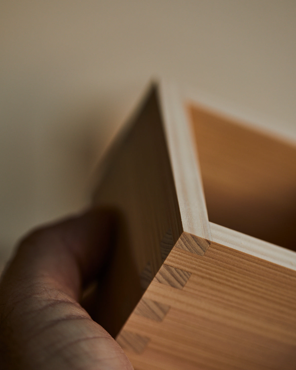 Corner of a Hinoki sake cup held in the hand, joints visible