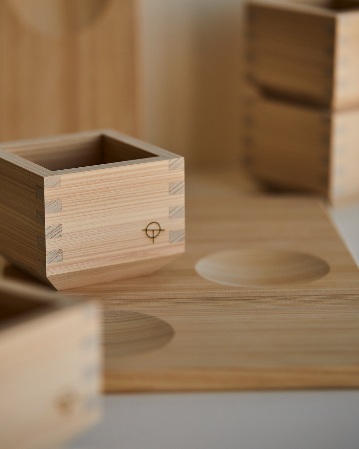 Hinoki sake cup on its serving tray, second tray leaning behind