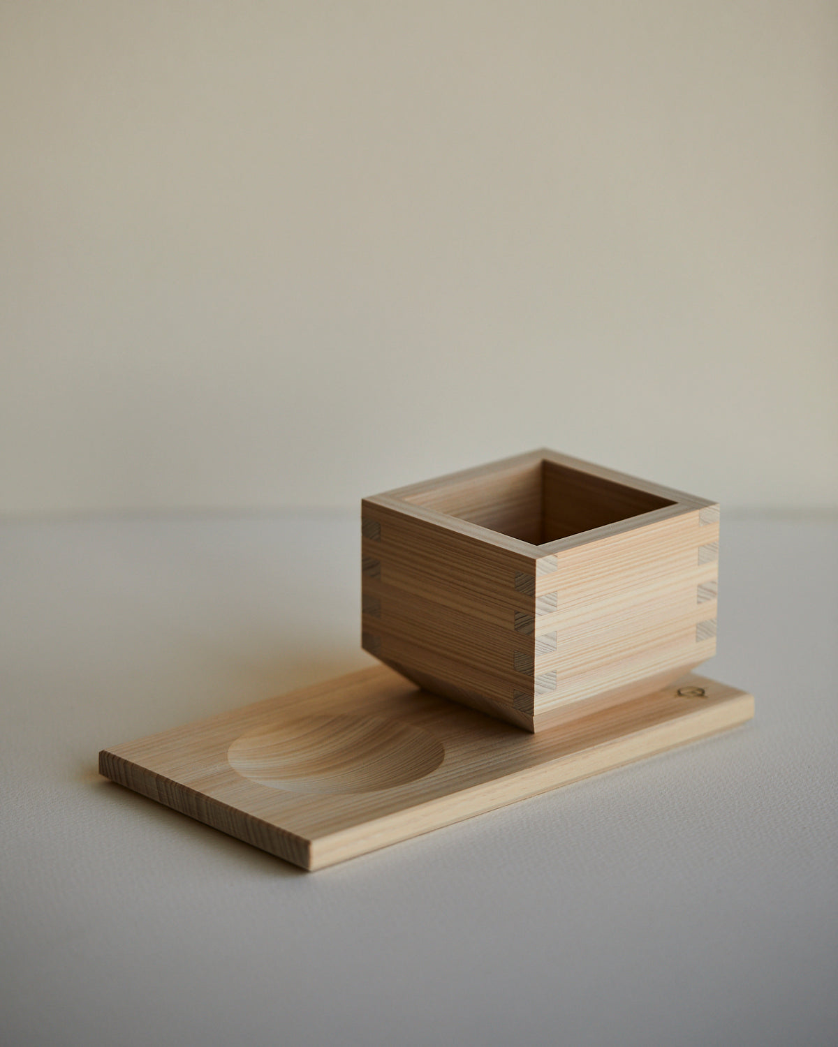 Hinoki sake cup on the serving tray beside the carved hollow